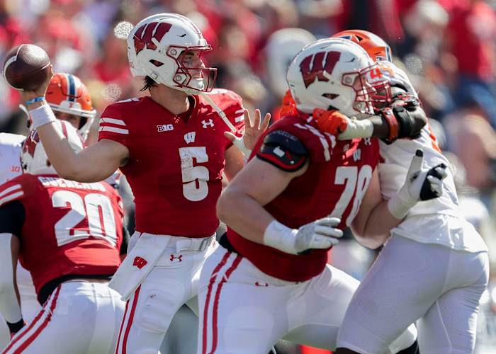 Graham Mertz throwing the football against Illinois with a pass-rusher in his face.
